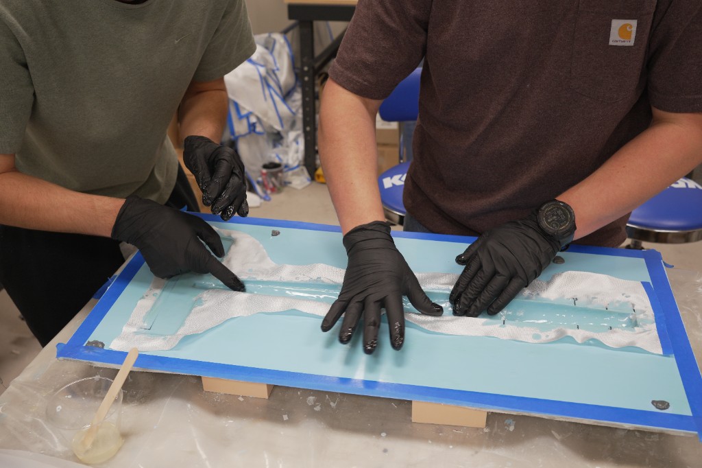 Composite layup: fiberglass being laid into a fuselage mold channel